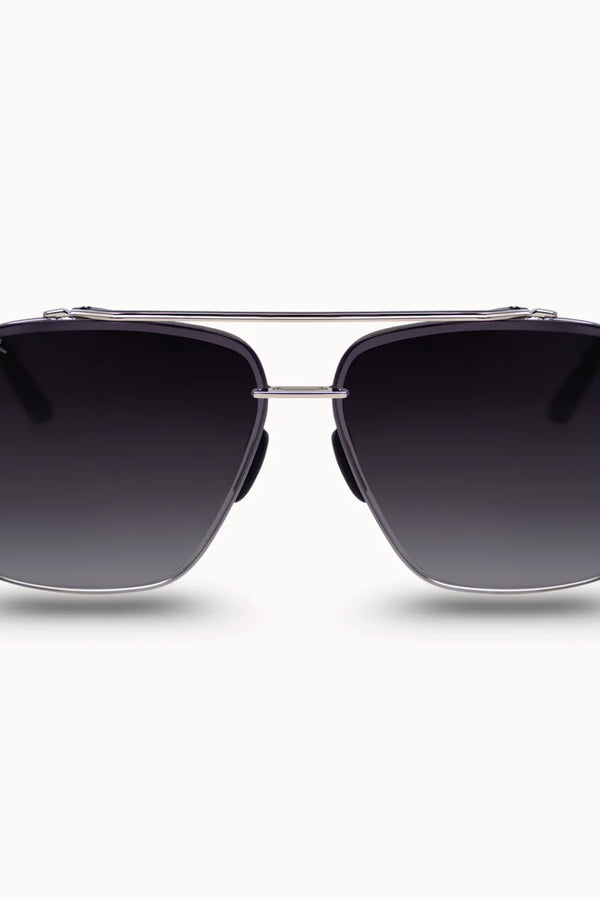 A pair of square aviator-style sunglasses with dark gray gradient lenses, a silver metal frame, and a double bridge, shown against a light gray background.