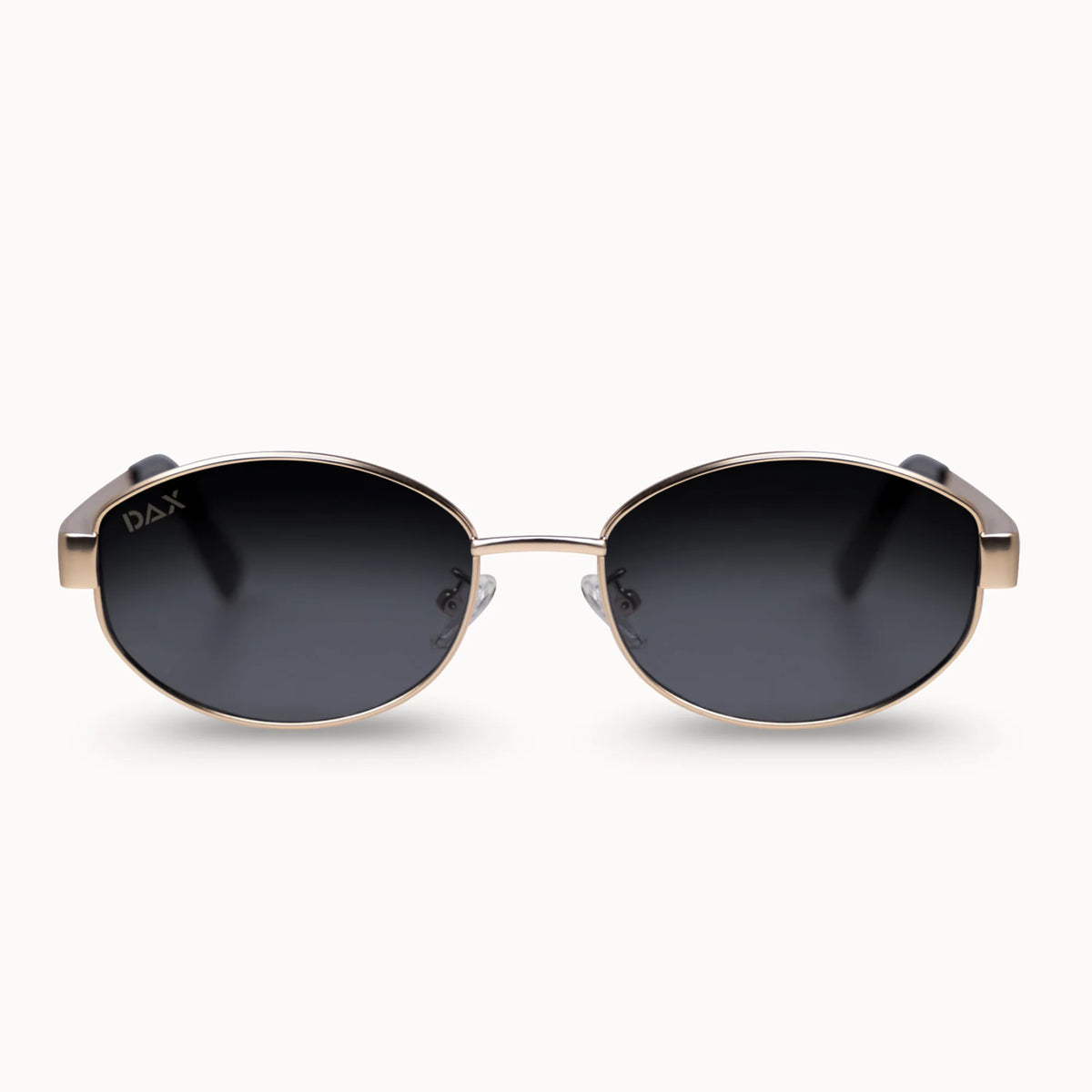 Oval sunglasses with a thin gold metal frame and dark gray gradient lenses, shown from the front on a light cream background.