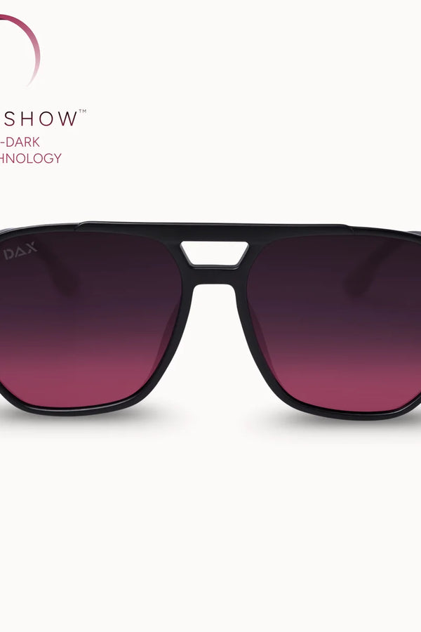 A pair of aviator-style sunglasses with a matte black frame and gradient dark purple to magenta lenses, shown against a light cream background with the Smokeshow brand logo in the upper left.